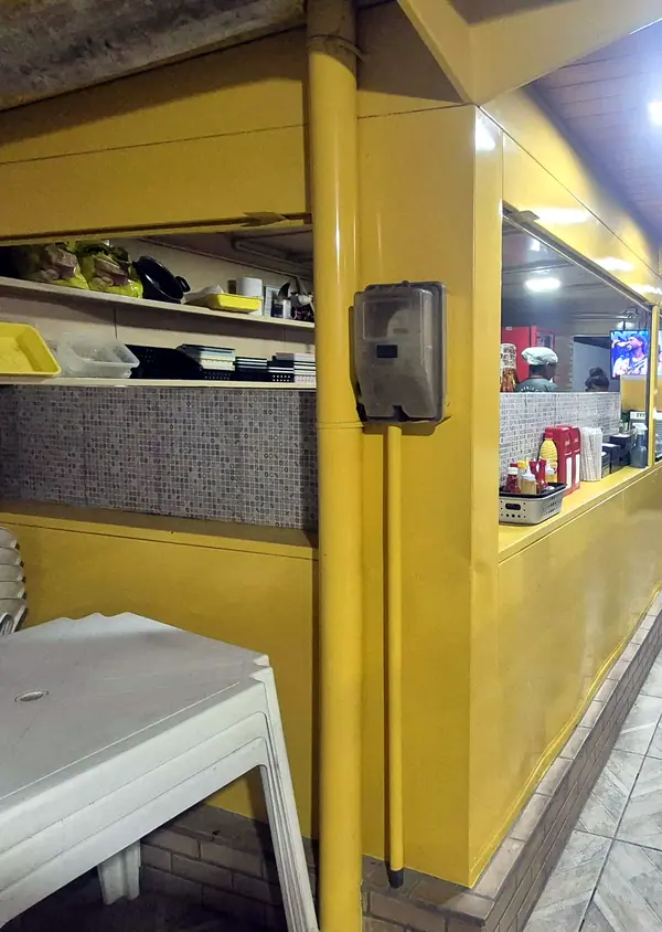 Balcão amarelo da Barraca do Baiano, com a cozinha à vista e o piso de cerâmica ao lado